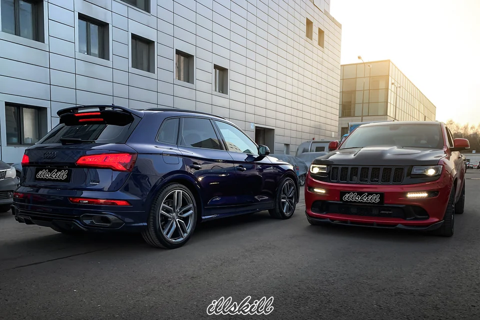 Синий Audi Q5 и красный Jeep Grand Cherokee у здания мастерской