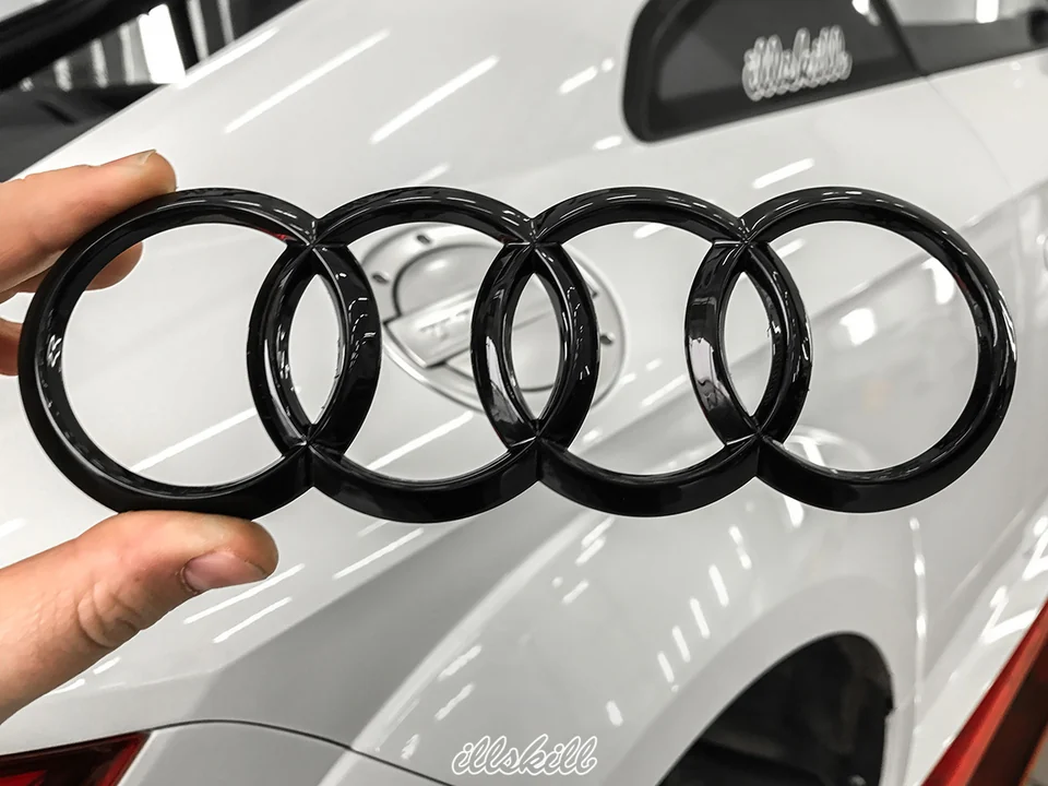 Чёрная эмблема Audi в руке мастера