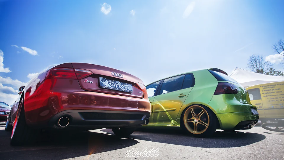 Красный Audi S5 рядом с зелёным Volkswagen на автомобильном фестивале