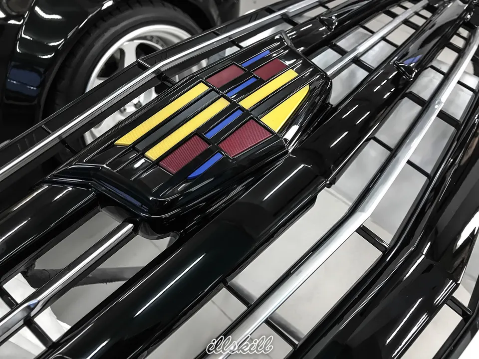 Цветная эмблема Cadillac на чёрной решётке радиатора
