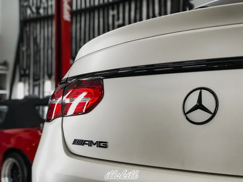 Чёрная эмблема Mercedes-Benz на белой крышке багажника
