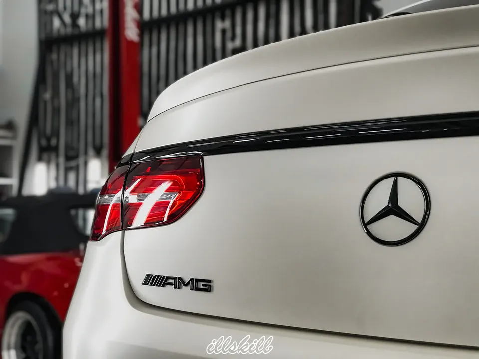 Чёрная эмблема Mercedes-Benz на белой крышке багажника