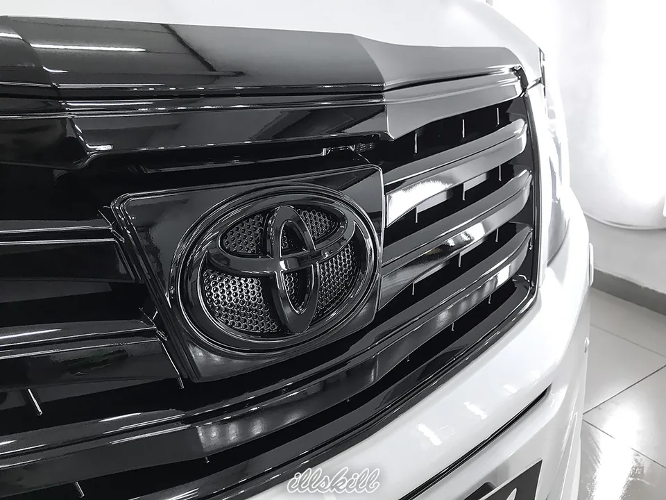 Чёрная эмблема Toyota и планки решётки крупным планом
