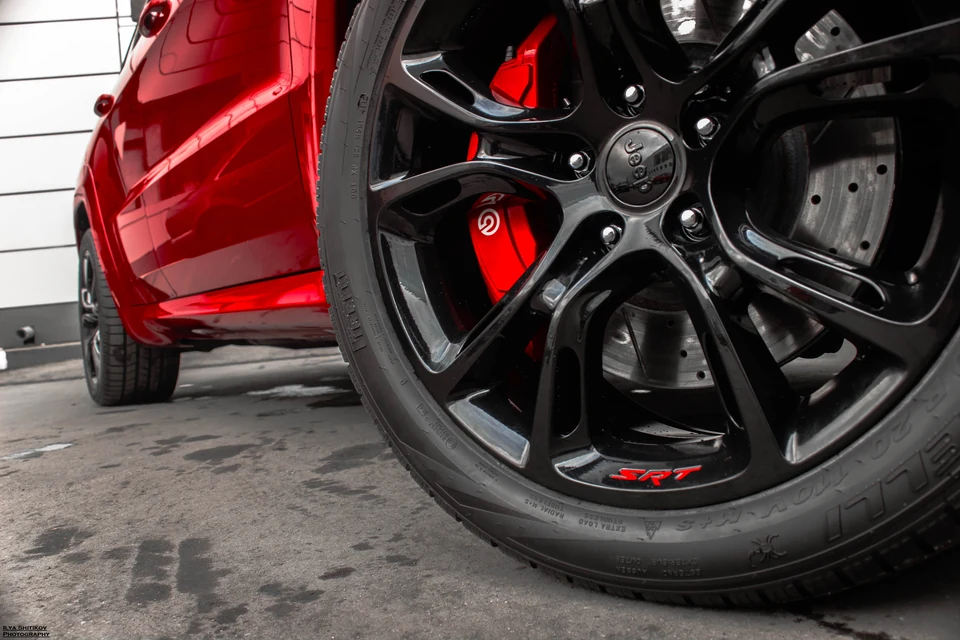 Чёрный колёсный диск с надписью SRT и красный суппорт.