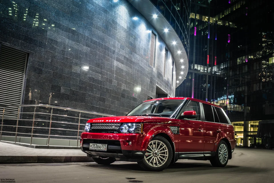 Красный Range Rover Sport у освещённого здания