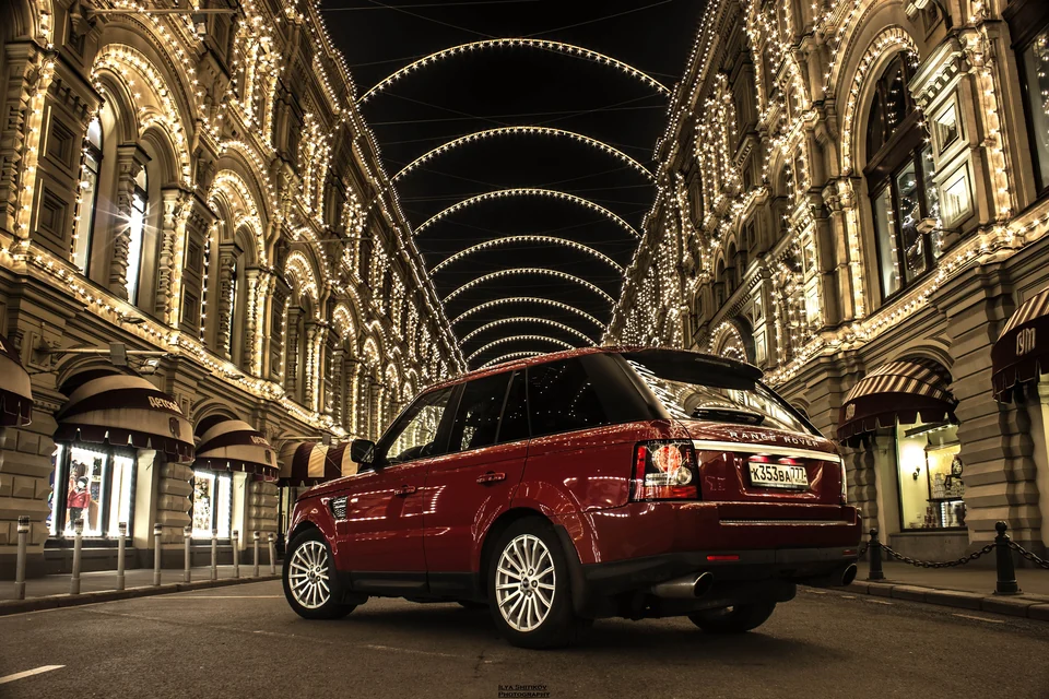 Красный Range Rover Sport на вечерней улице, вид сзади
