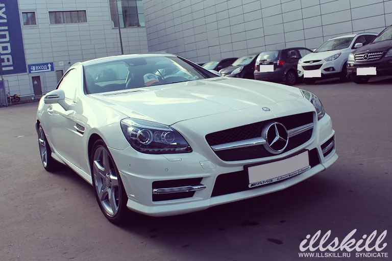 Белый Mercedes-Benz SLK 200 спереди сбоку: решётка с эмблемой и серебристые диски.