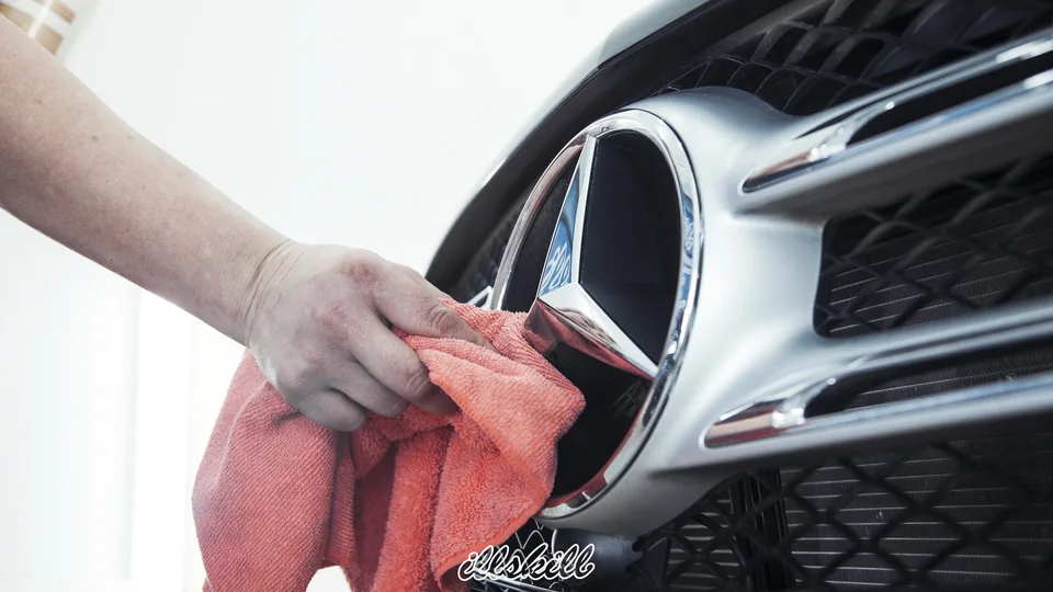 Мастер протирает салфеткой эмблему Mercedes-Benz