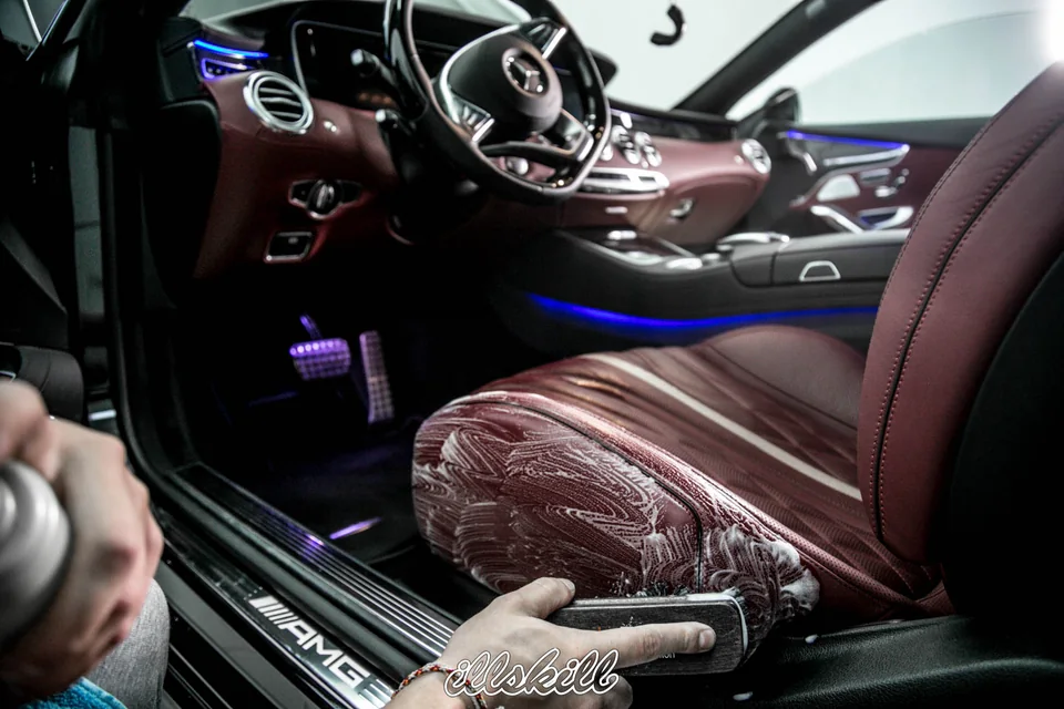 Мастер очищает бордовое сиденье Mercedes-Benz