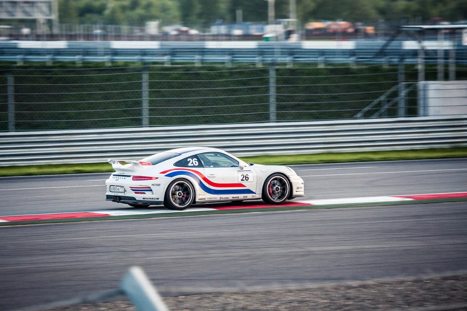 Белый Porsche 911 с полосами на трассе, вид сбоку