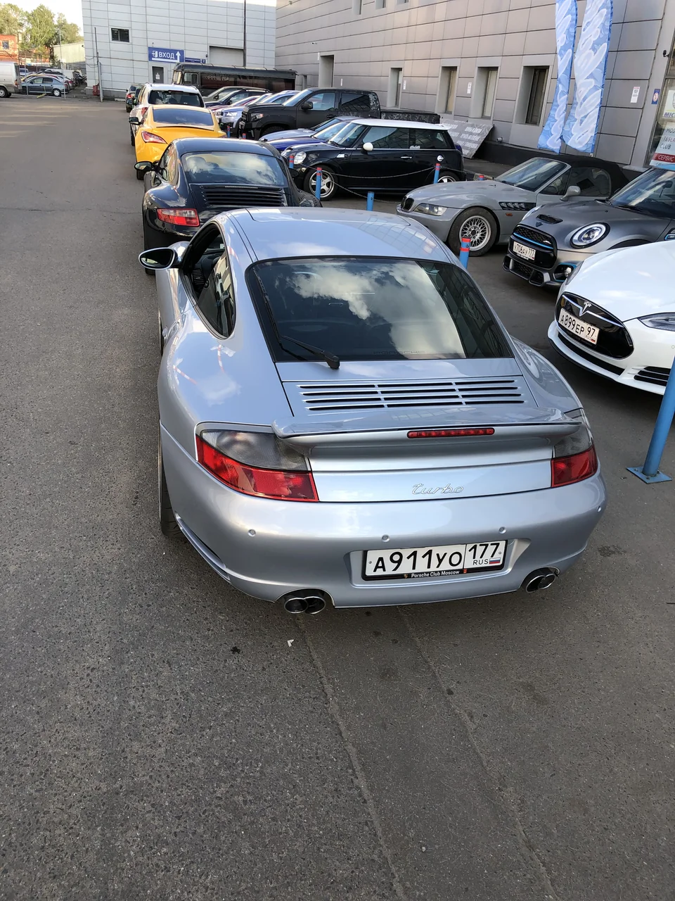 Серебристый Porsche 911, вид на заднюю часть кузова и антикрыло.