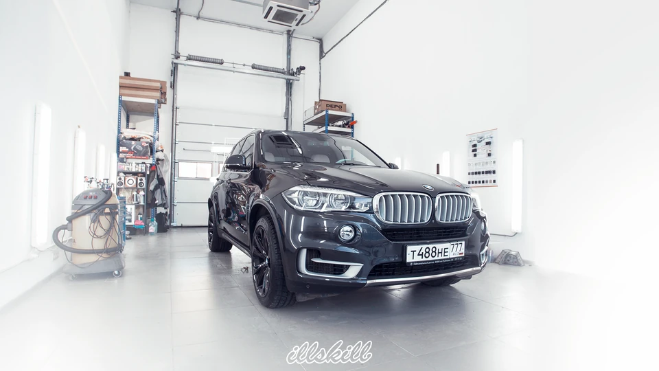 Тёмный BMW X5 с чёрными многоспицевыми дисками в мастерской