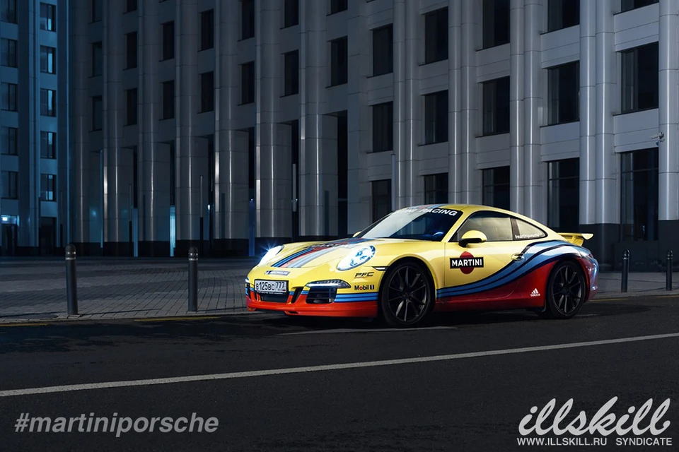 Жёлтый Porsche 911 с цветной графикой и тёмными дисками на вечерней улице
