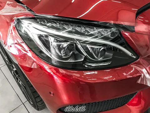 Плёнка на фаре красного Mercedes-Benz во время нанесения