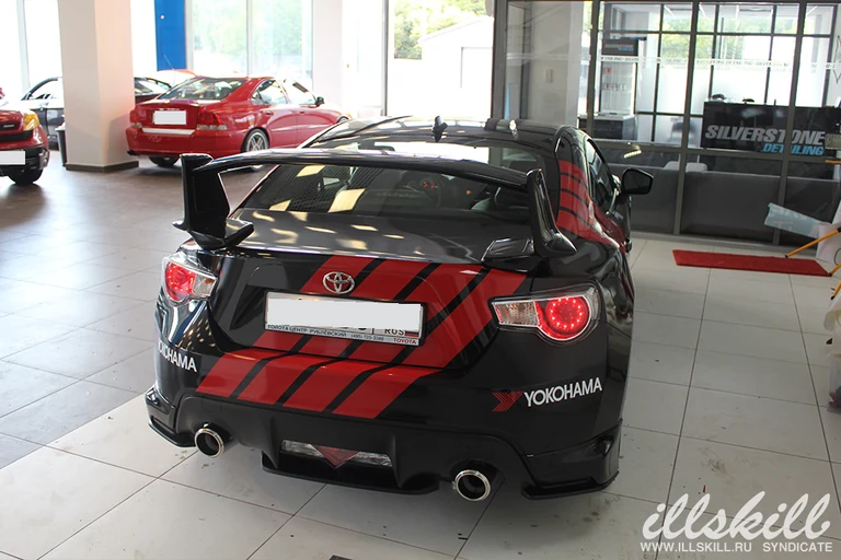 Toyota GT86 сзади в мастерской: полосы на багажнике и бампере.